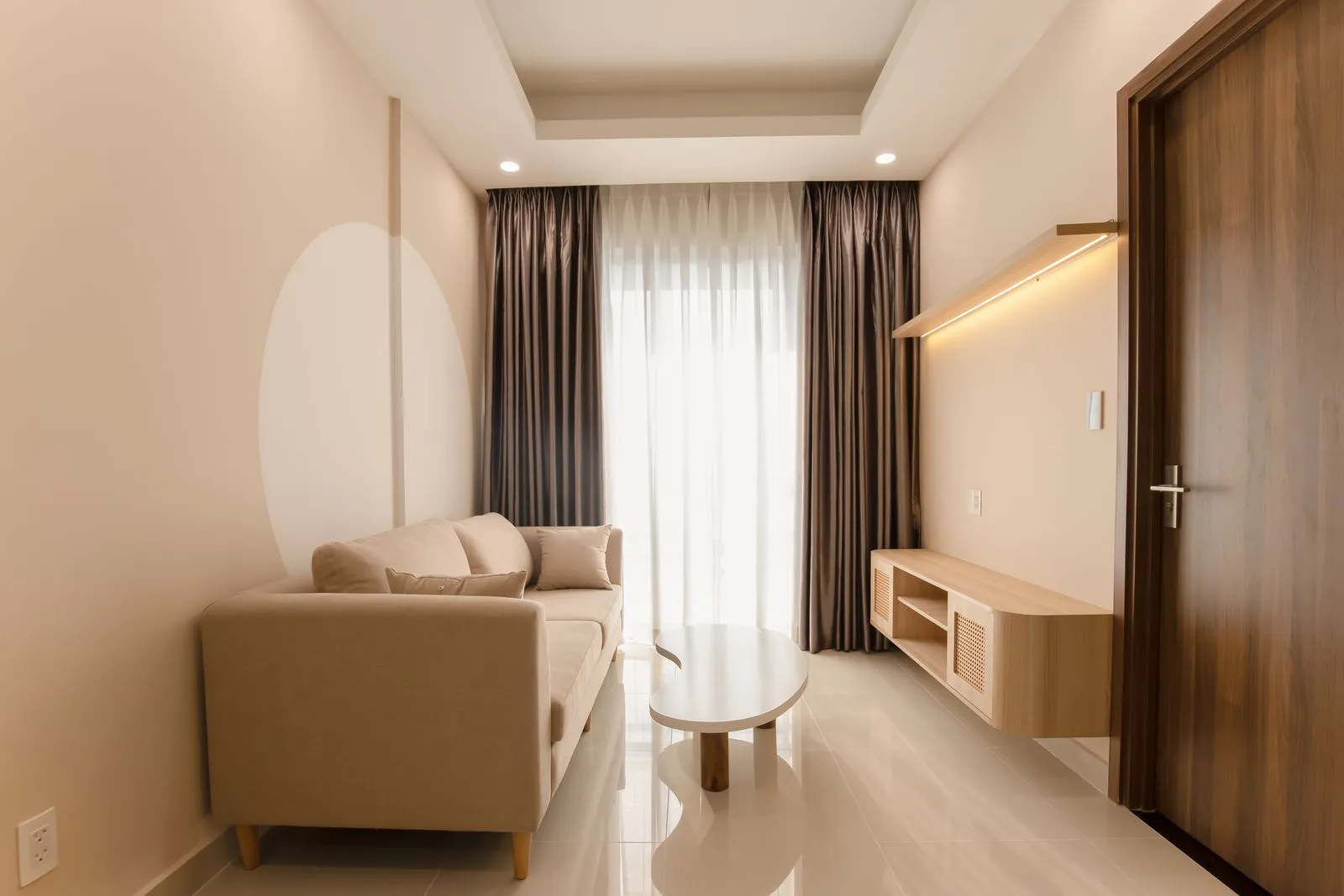 A minimalist living room with a beige sofa, modern table, and soft lighting.